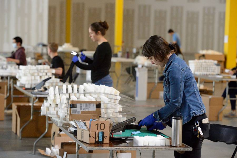 Volunteers assemble face shields in a warehouse