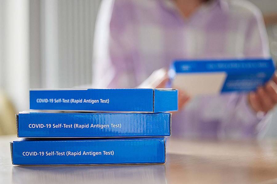 Closeup of a woman at home reading instructions for COVID-19 rapid antigen self-testing kits