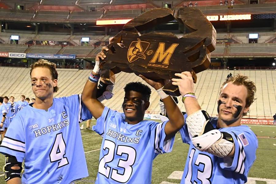 Hopkins players hoist the rivalry trophy after a win against Maryland