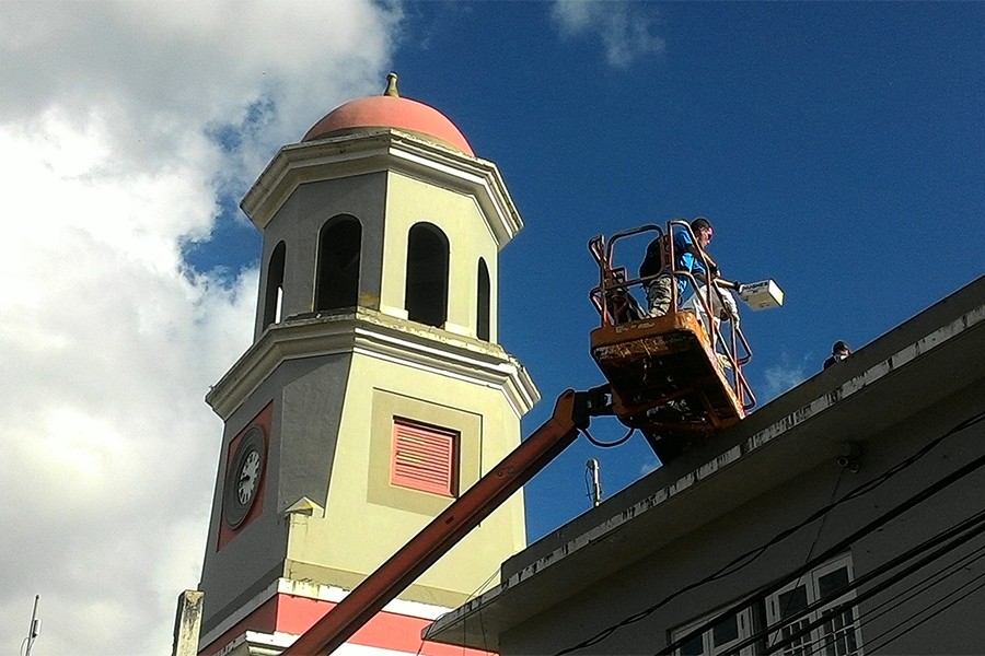 Crane elevates man to a rooftop position with church steeple in background