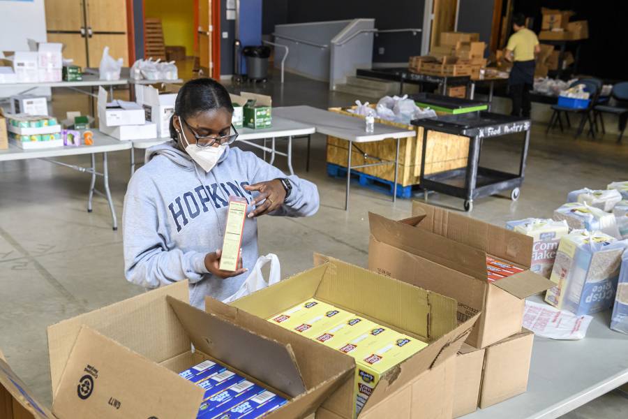 A Johns Hopkins student volunteer from the Center for Social Concern sorts food for distribution at Henderson-Hopkins 