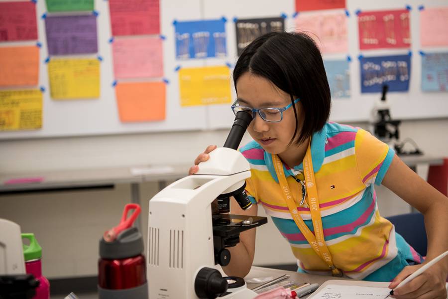 A girl looks through a microscope