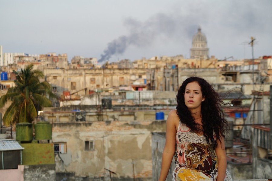 A woman sits on a rooftop while Havana sprawls out behind her