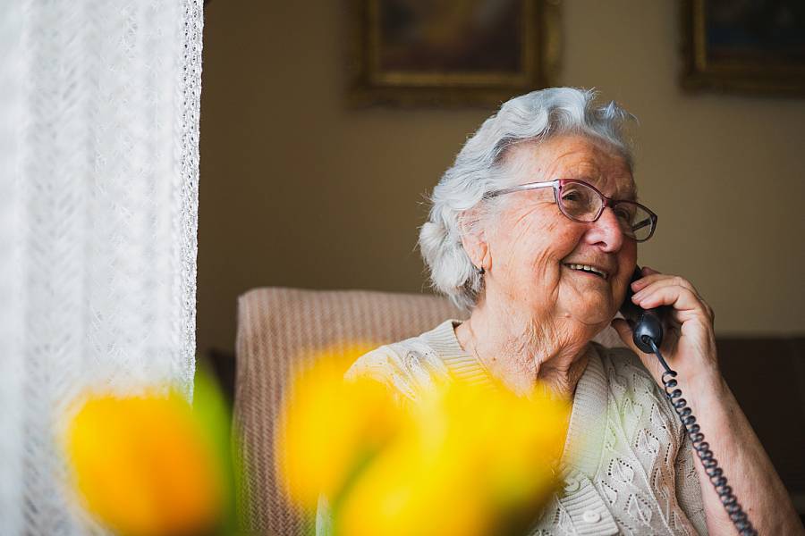 Elderly woman smiling while talking on the phone