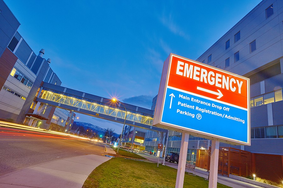 Red emergency sign with arrow pointing right outside of hospital