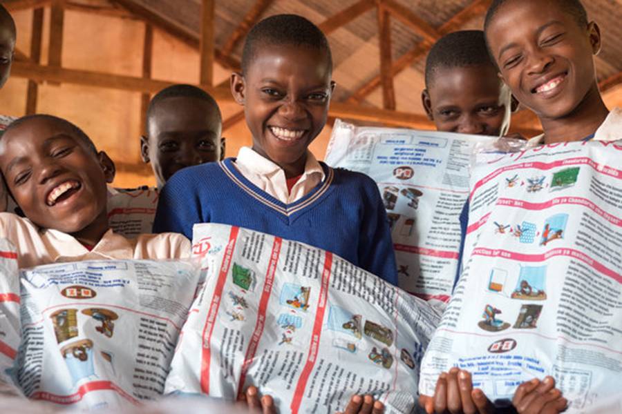 Schoolchildren receive free bed nets during a distribution in Tanzania. 