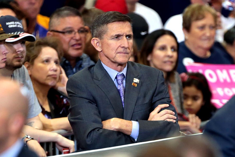 Michael Flynn stands with arms crossed in front of Trump supporters at rally