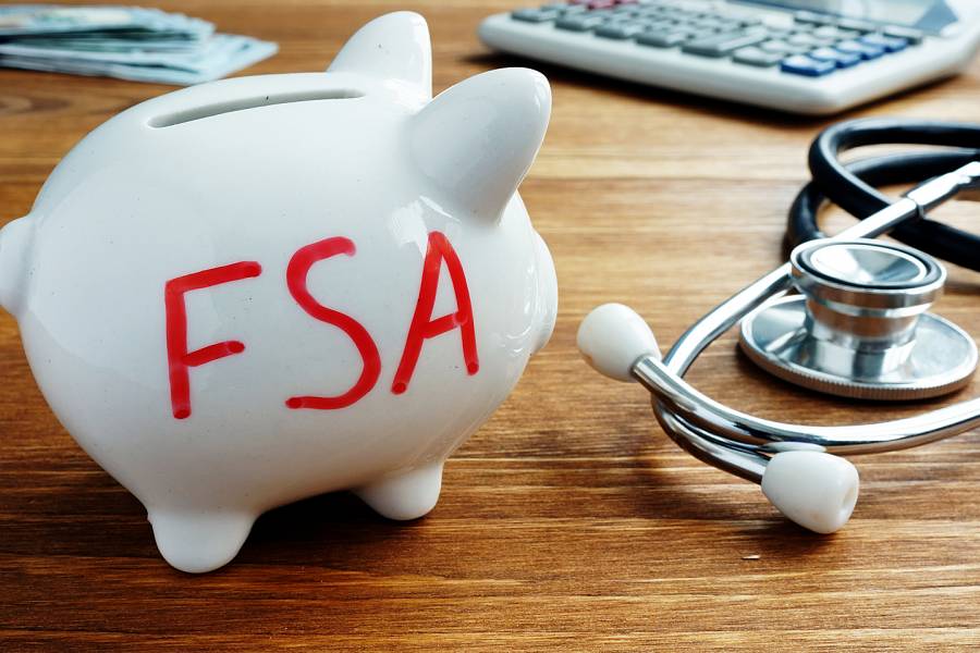 Piggybank with FSA written on it, next to a stethoscope