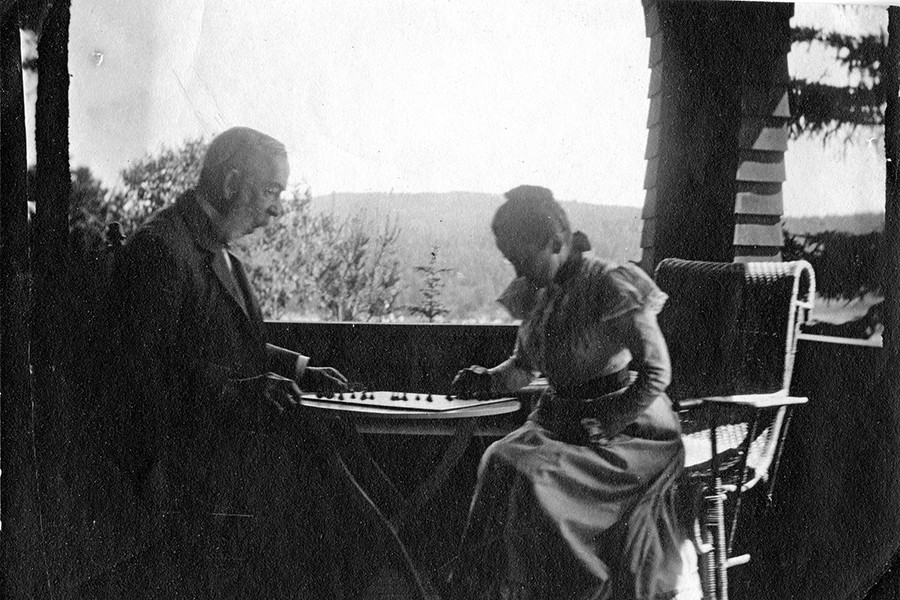 In a grainy black and white photo, two people play chess