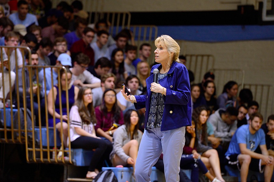 Neuroscientist Linda Gorman holds a microphone and addresses a gym full of undergraduate students