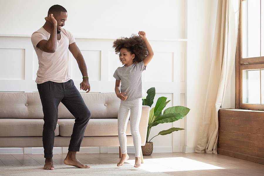 Man and daughter dancing energetically in the living room