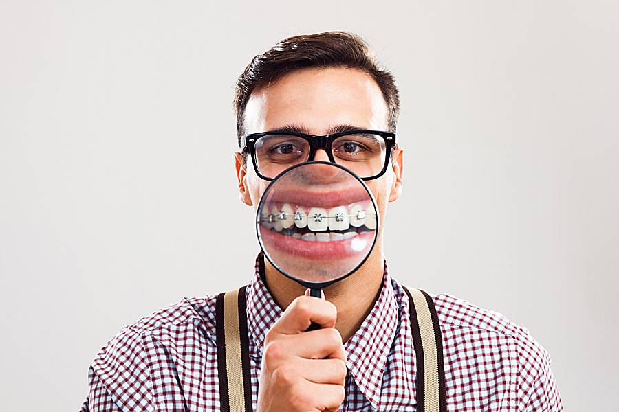 Man wearing eyeglasses and also braces on his teeth