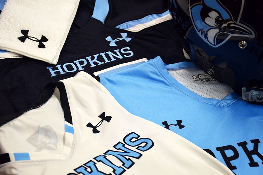 Assortment of Hopkins athletics jerseys in blue, white, black featuring Under Armour logos