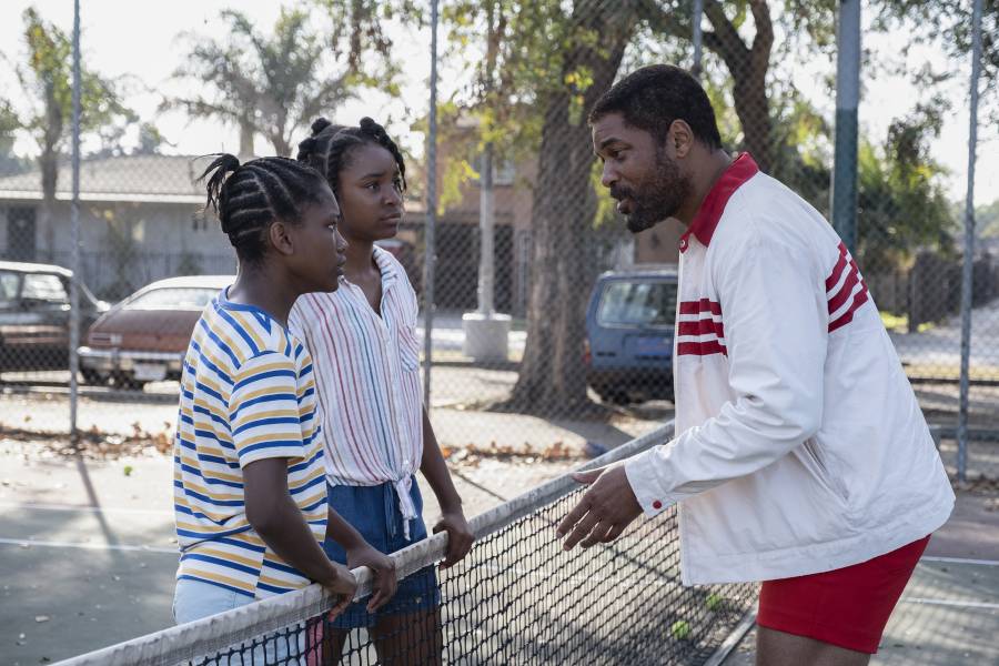 From left to right, Demi Singleton as Serena Williams, Saniyya Sidney as Venus Williams, and Will Smith as Richard Williams in a scene on an outdoor tennis court from the film King Richard.