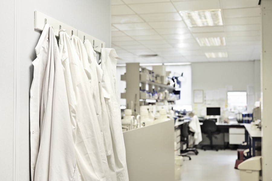 A row of lab coats hang on hooks in a lab