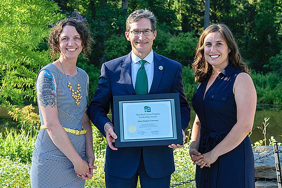 Homewood campus recycling manager Leana Houser and recycling manager Brigid Gregory receive the JHU award from Ben Grumbles, secretary of the Maryland Department of the Environment.
