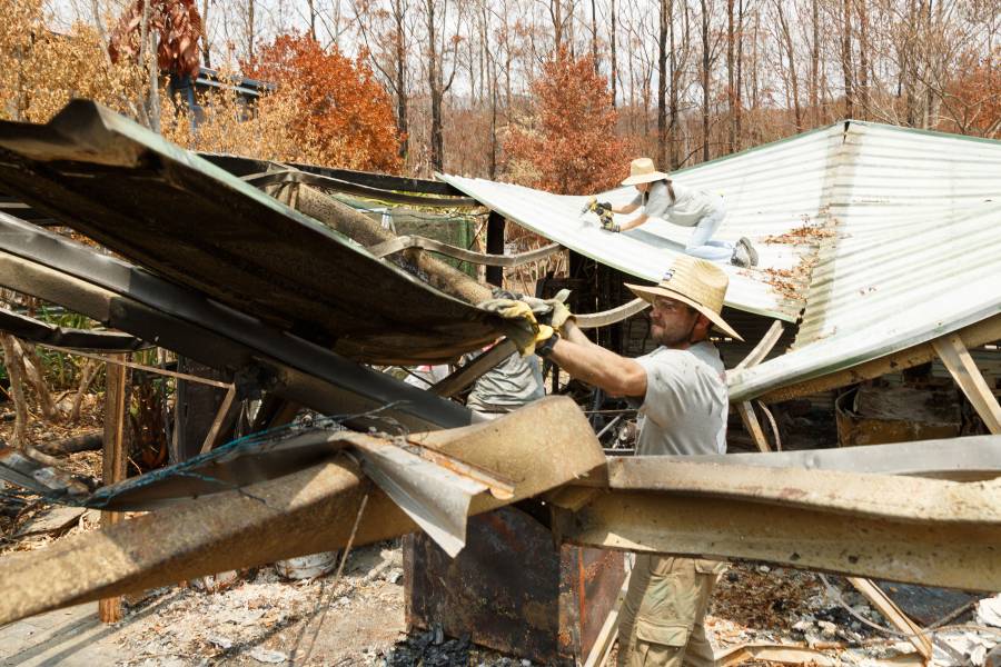 Alum William McNulty sorts through the rubble of a home destroyed by the Australian bush fires