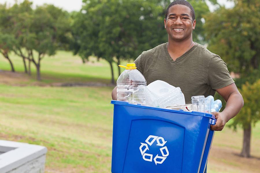 Man carrying recycling bin in a public park
