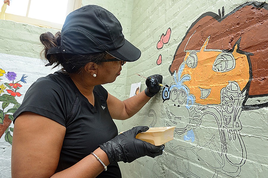 Cherita Hobbs paints a mural at the Family Recovery Program during the July launch of the Johns Hopkins Takes Time for Baltimore program.