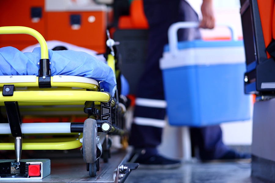 Image shows a stretcher in the foreground and a person carrying a cooler in the background