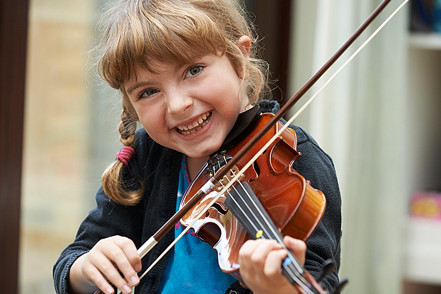 Smiling young girl with braids plays the violin