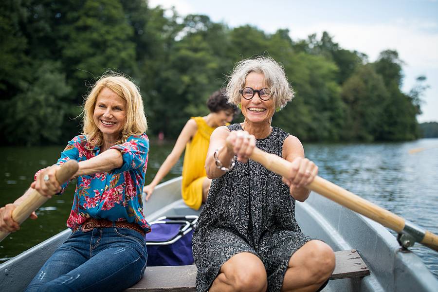 Two happy senior women rowing side-by-side