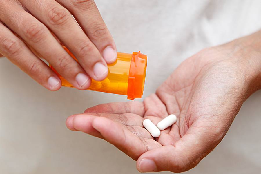 Woman pouring pills into hand