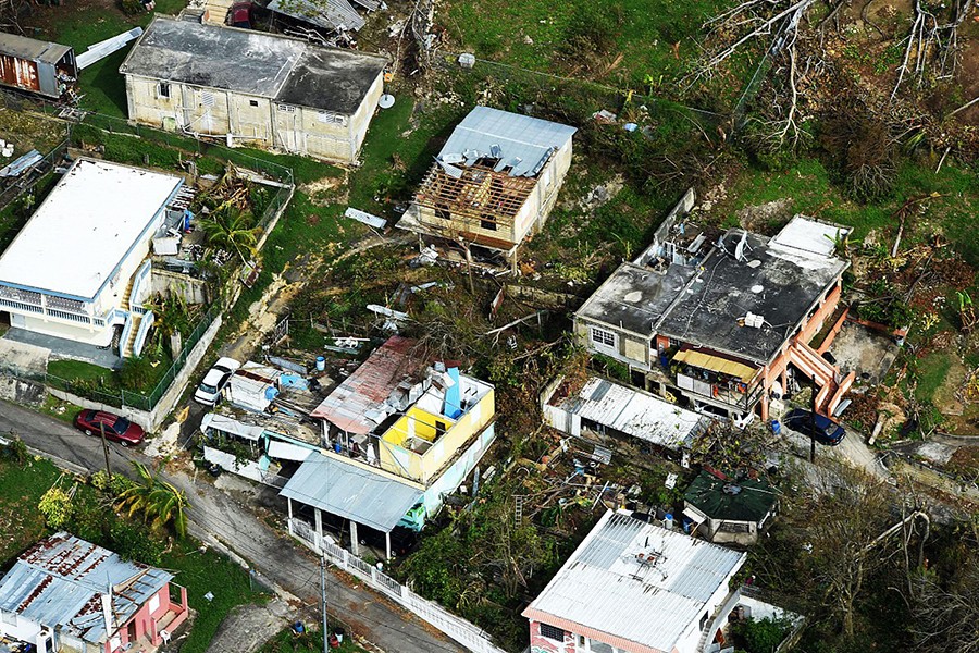 The roofs of houses are torn off, and downed trees and debris litters the ground