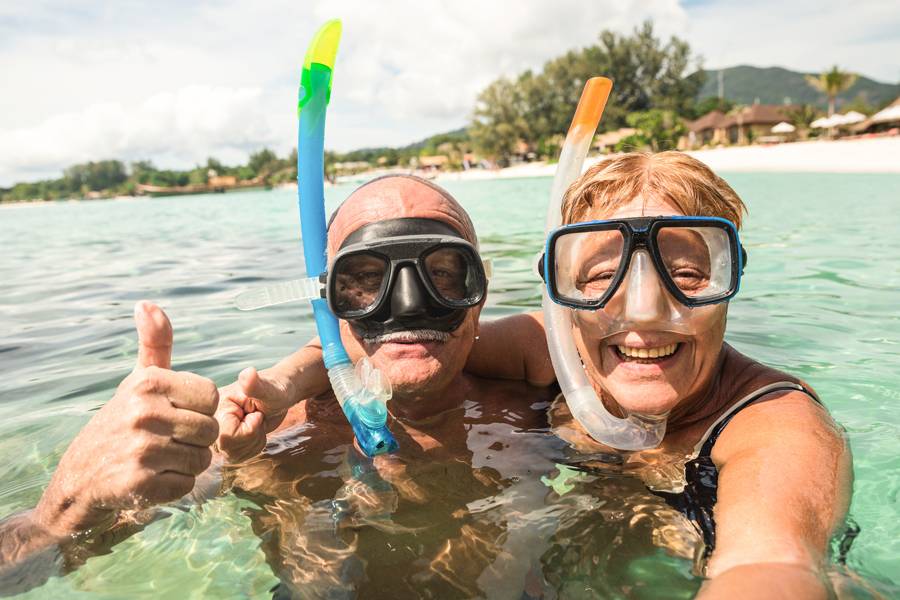Smiling senior couple in sea wearing snorkels