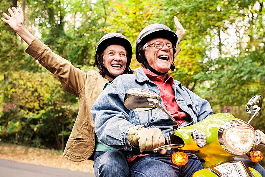 Happy older couple riding a motorcycle