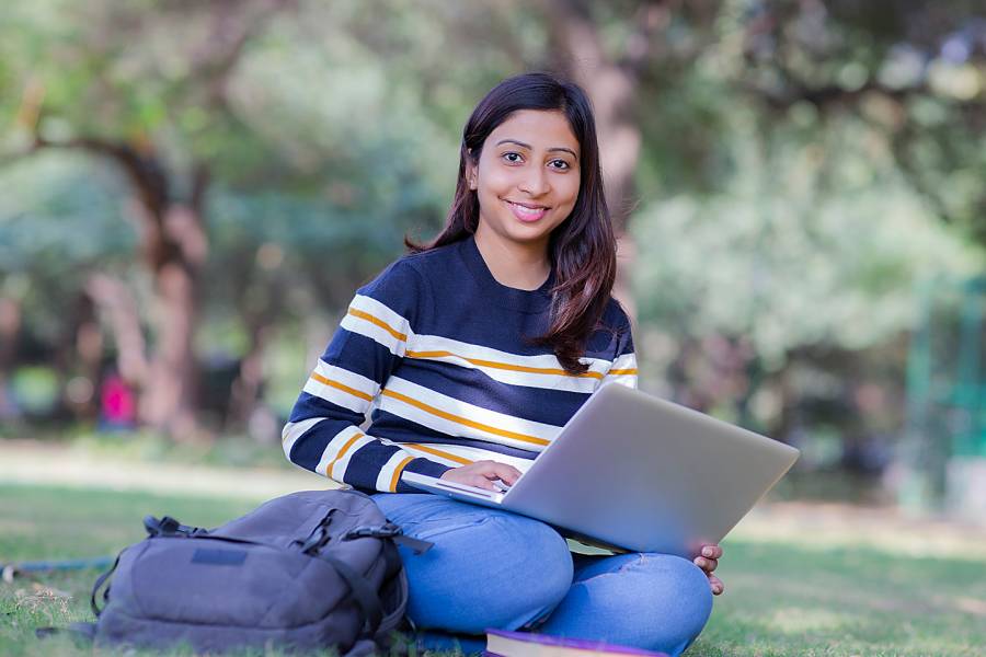 Young woman with laptop sitting on school campus