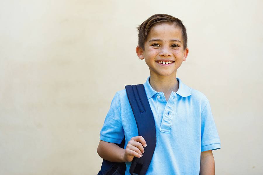 Smiling young boy in blue uniform shirt
