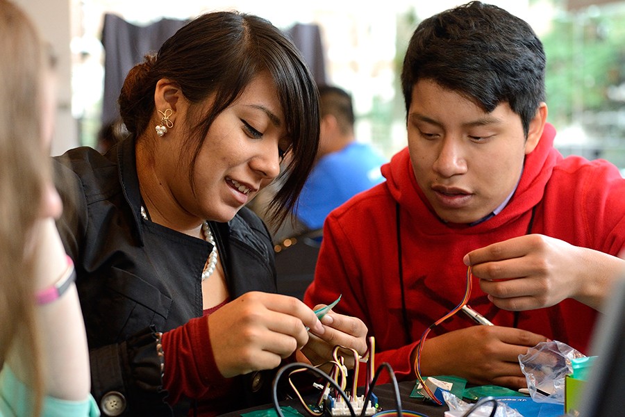A young woman and young man work with an electrical circuit board