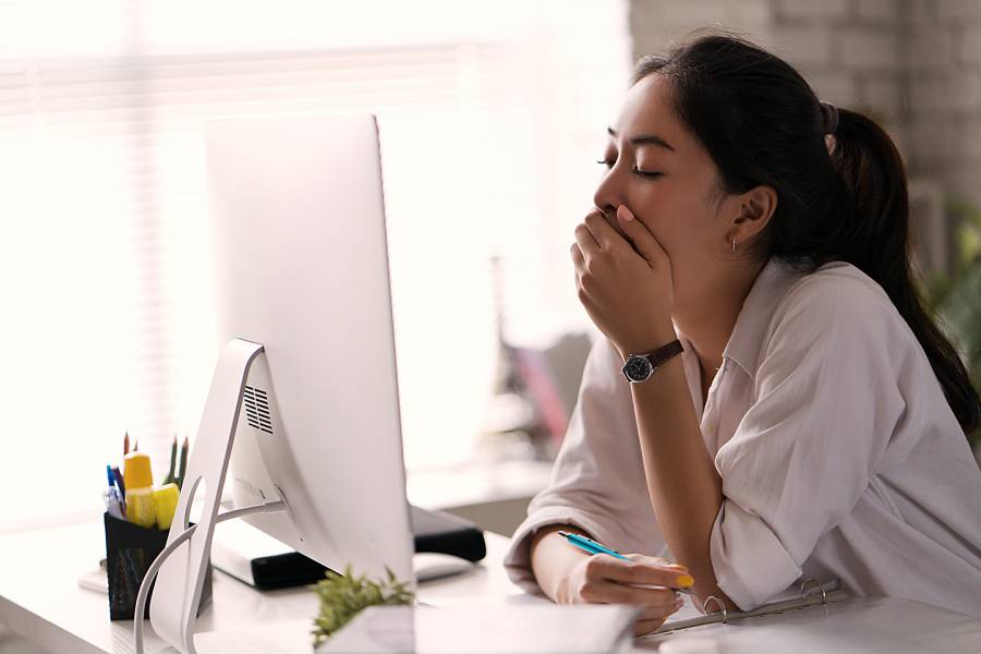 Woman yawning in front of her computer