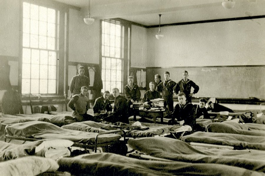 Black and white photo shows young soldiers in training lounging in their barracks