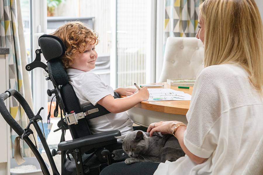 Boy in a wheelchair at a table with his mother