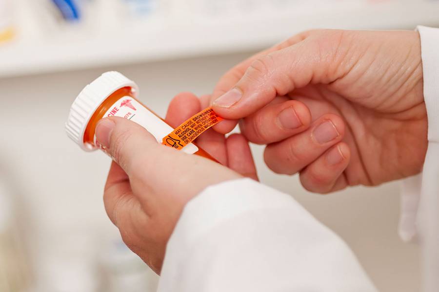 Pharmacist applying a drug-warning label to a pill container
