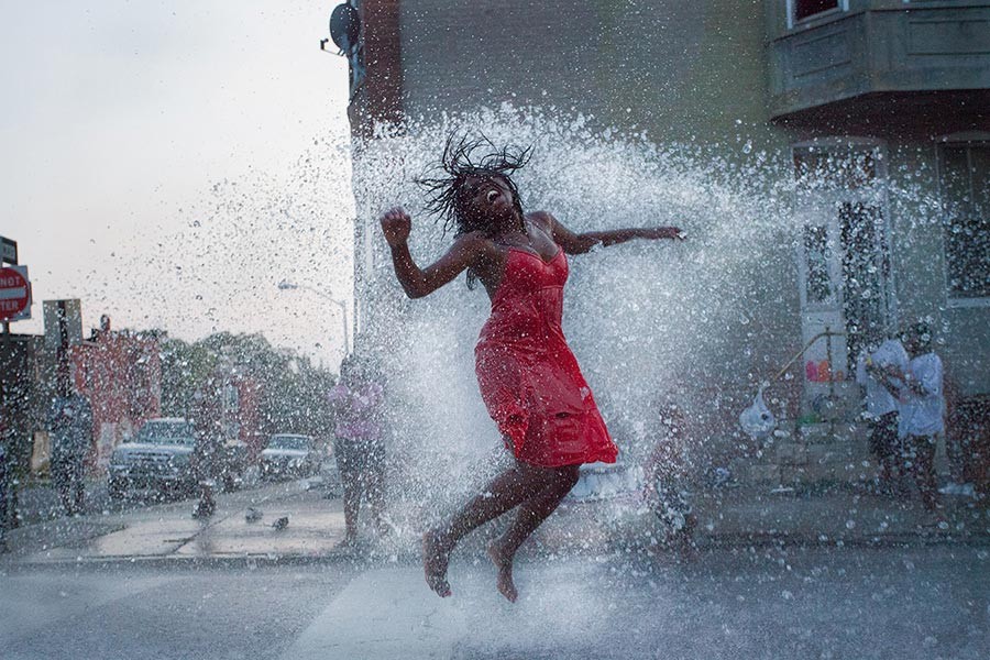 Woman jumping in stream of a fire hydrant