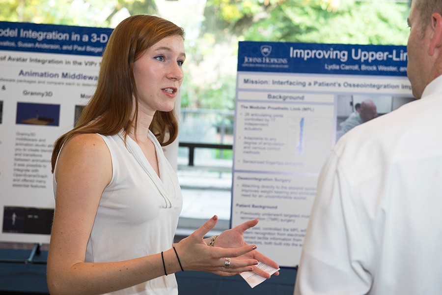 Lydia Carroll speaks with a poster session attendee