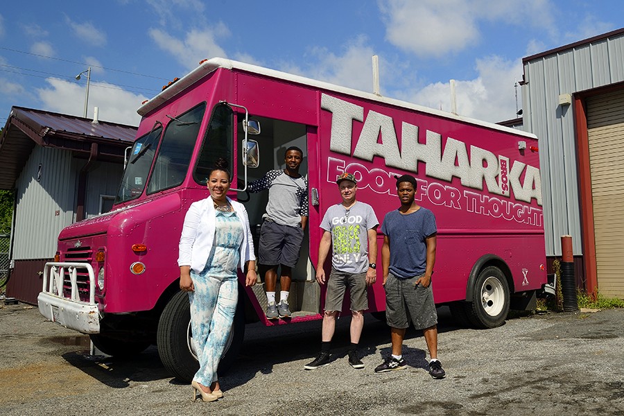 Four people pose in front of magenta Taharka Brothers ice cream truck