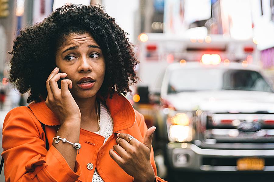 Concerned-looking woman on phone near cars in big city