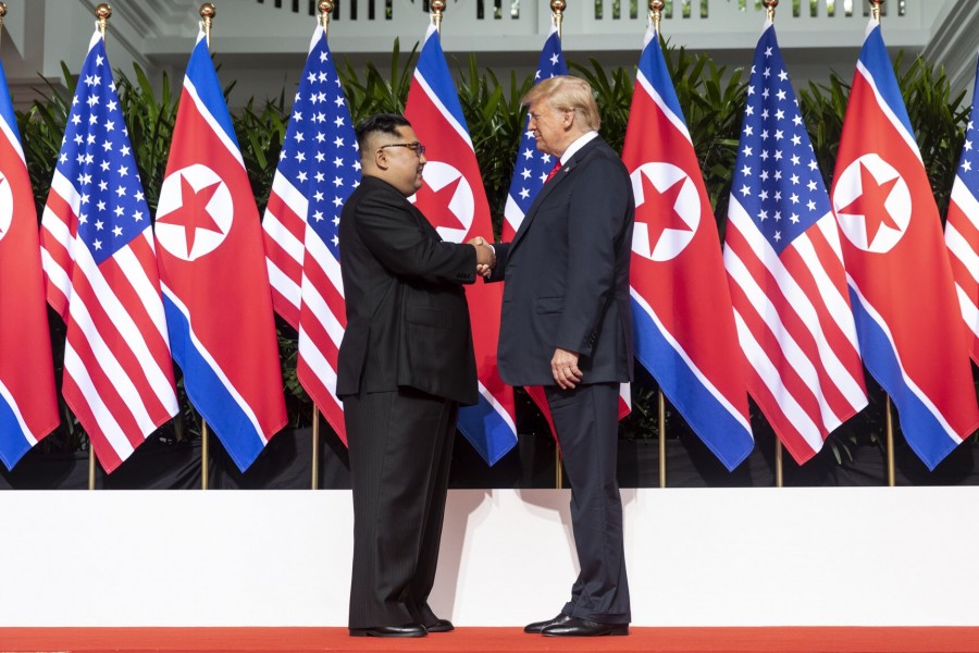 Trump and Kim shake hands in front of backdrop of U.S. and North Korean flags