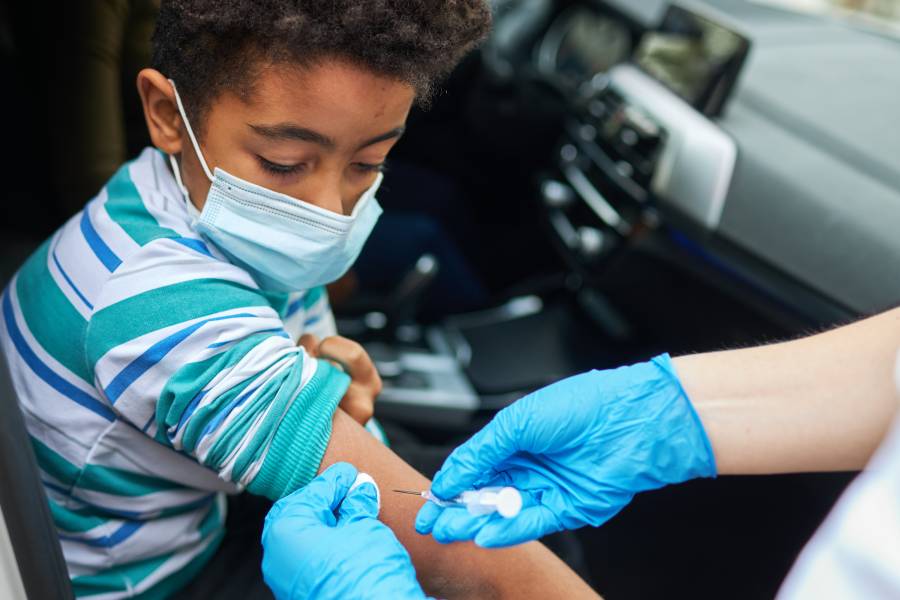 A kid gets vaccinated in a drive-through clinic