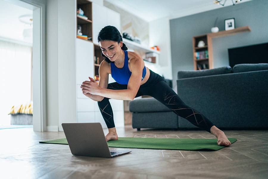 Woman exercising in front of a laptop placed on the floor