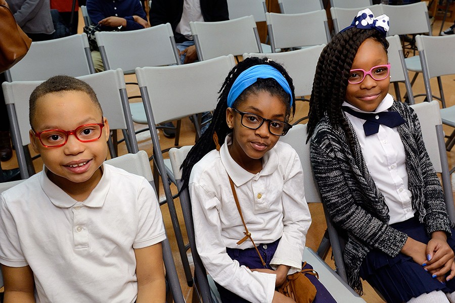 Three children wearing glasses smile for the camera
