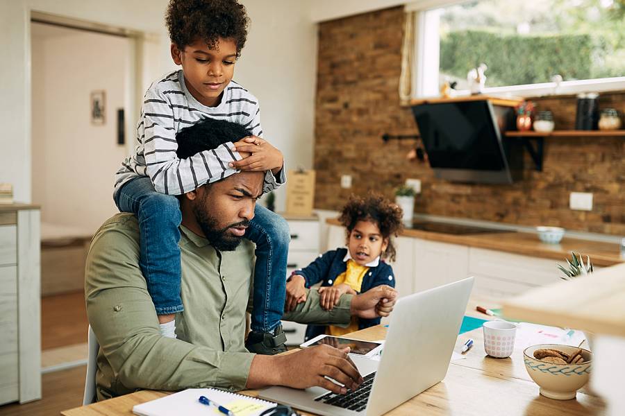 Man working on laptop while two young children try to get his attention