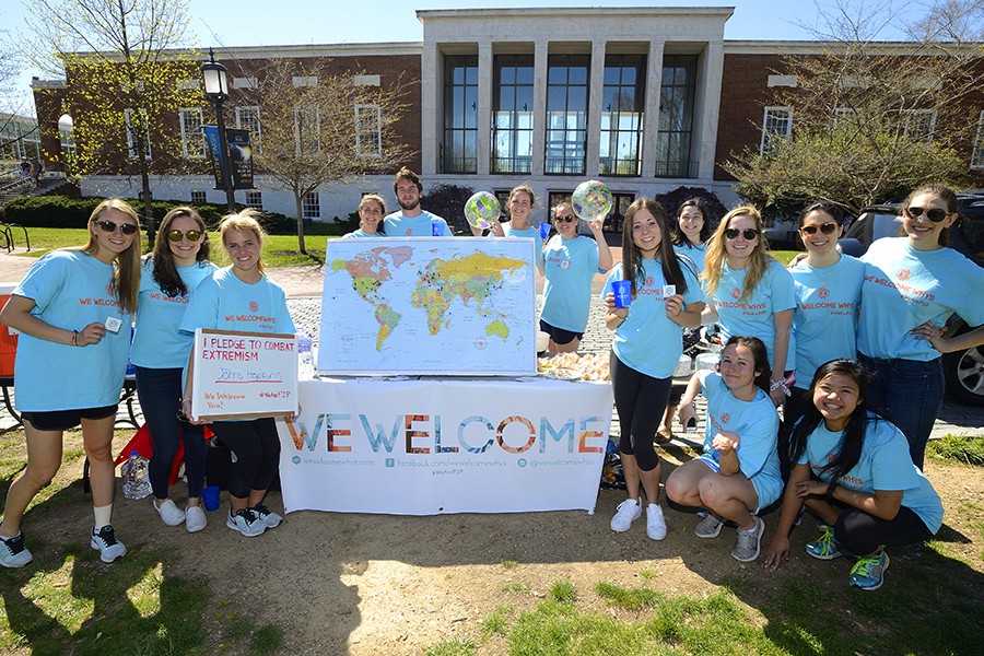 Students in blue t-shirts pose with map, globes, and 