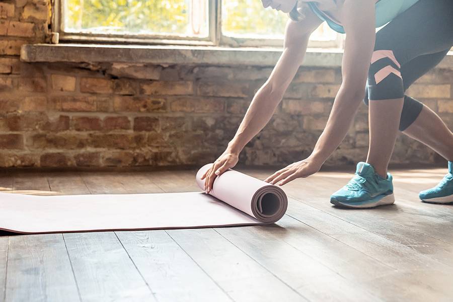Woman laying exercise mat on the floor of her home