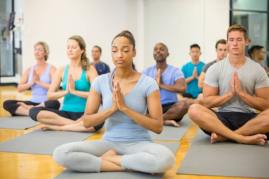 A group of multi-ethnic adults meditating on yoga mats
