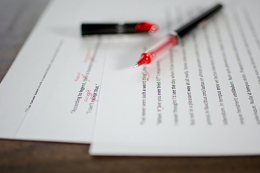 A printed document shows editing marks done in red ink